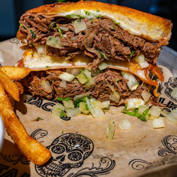 A Talkin' Tacos birria quesadilla with shredded beef, onions, and cilantro, served with fries.