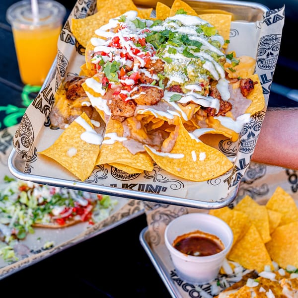 A tray of Talkin' Tacos nachos with chicken, guacamole, pico de gallo, and sour cream.